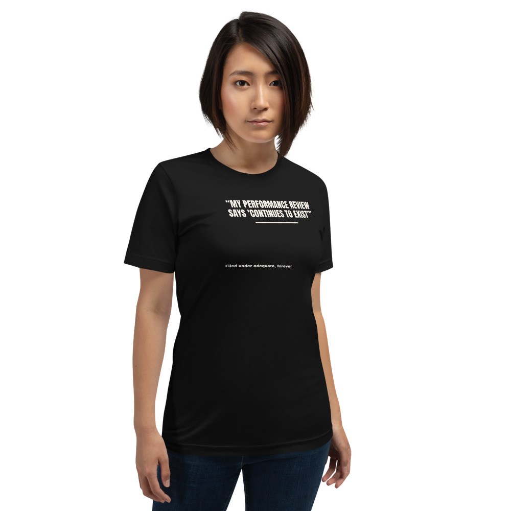 MY PERFORMANCE REVIEW SAYS 'CONTINUES TO EXIST' — printed on a black t-shirt